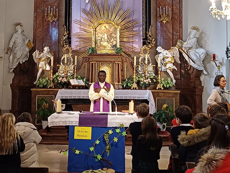 Pfarrer (von vorne) hält die heilige Messe. Kinder (von hinten) sind die Messebesucher.